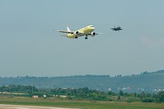 Самолет МС-21 в небе, расправивший свои крылья над городом