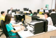 Мама на работе с документами Трудового кодекса, улыбающаяся и планирующая уходить пораньше