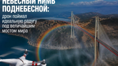 Дрон запечатлел радугу под мостом с небесным фоном.