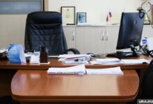Айтишник, стоящий перед зданием университета, с удивленным выражением лица