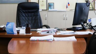 Айтишник, стоящий перед зданием университета, с удивленным выражением лица