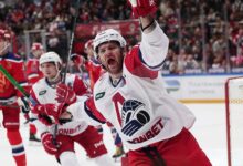 Александр Радулов с хоккейной шайбой на фоне арены КХЛ