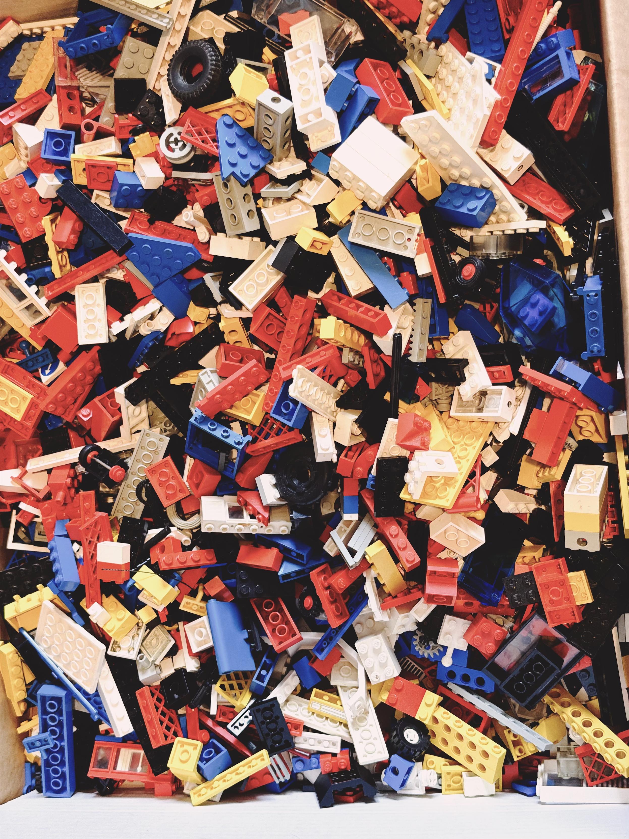 A large box filled with vintage LEGO bricks in red, blue, white, yellow and black, collected over several decades.